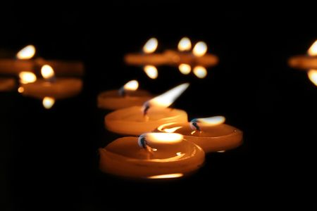 Candles floating on water by nightの写真素材