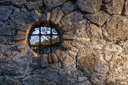 Round shaped window with a lattice in a stone fence. Round window. Window in a fence.の写真素材