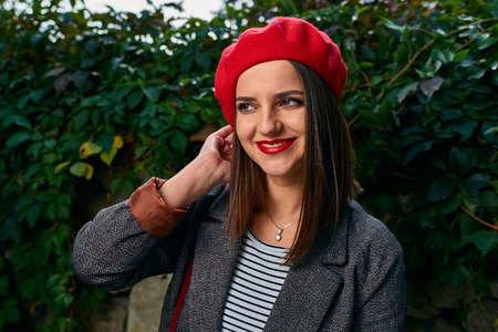 Portrait of a young woman in red beret fixing her hair.の写真素材