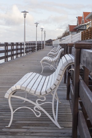 View across and empty deserted row of benches at the end of the pier looking towards the promenade.の写真素材
