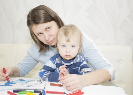 Mother and son are drawing together with pencils at tableの写真素材