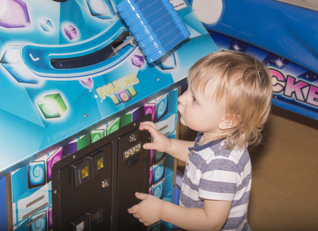 Child playing on the kids game machine at an amusement parkの写真素材