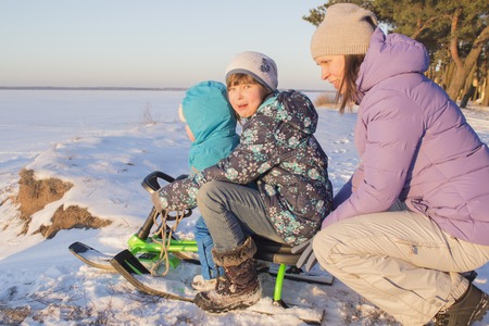 Mom and young children sledding down the hills.の写真素材