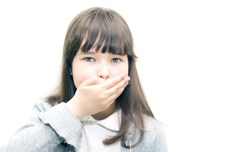Child teenager covers his mouth with his hand on a white background.の写真素材