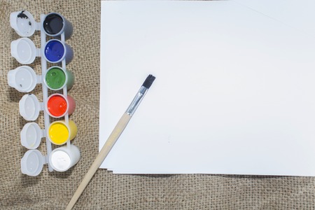 Set of watercolor paints, brushes for painting and blank white paper sheet of sketchbook. Top view.の写真素材