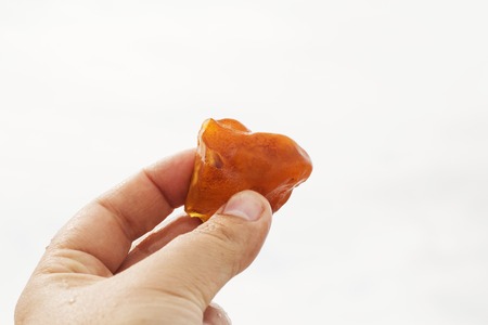 Amber in hand with a clear reflection of the palm on a light background. Bright light solar stone in...