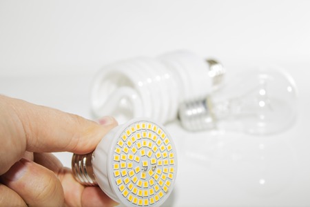 Several different led bulbs and compact fluorescent lamps and the male hand on a light backgroundの写真素材