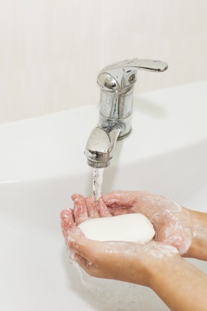 Washing of hands with soap under the crane with waterの写真素材
