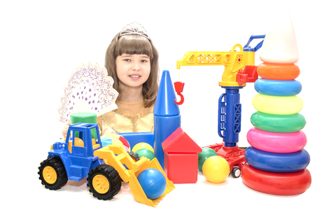 Teen girl in beautiful dress and bright colored toys on a white isolated background.の写真素材