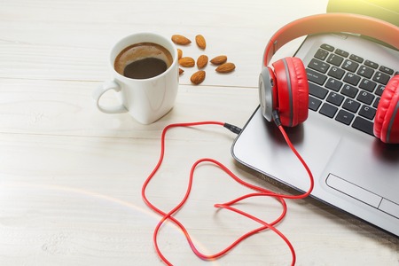 The laptop and red wooden headphones on a light background.の写真素材