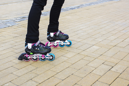 Legs of young woman rollerskating outdoors, foto