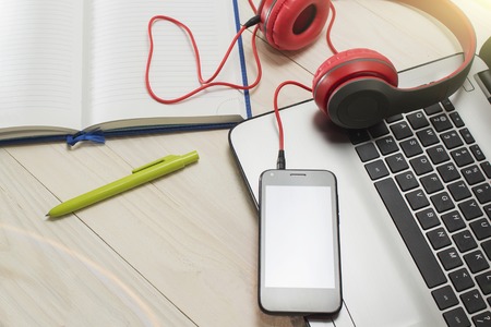 red headphones and phone on wooden light background