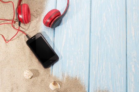 phone with headphones on sand in a summer beachの写真素材
