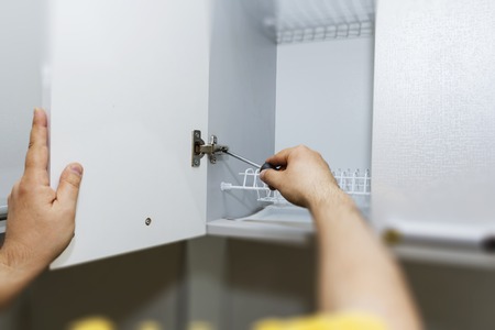 Assembly of kitchen furniture. Close-up of facade adjustment.