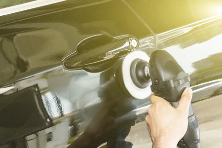 Car detailing - Hands with orbital polisher in auto repair shop. Selective focusの写真素材