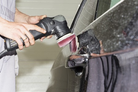 Car detailing - Hands with orbital polisher in auto repair shop. Selective focus