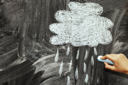 A cloud and a rain drawn with chalk on a blackboardの写真素材