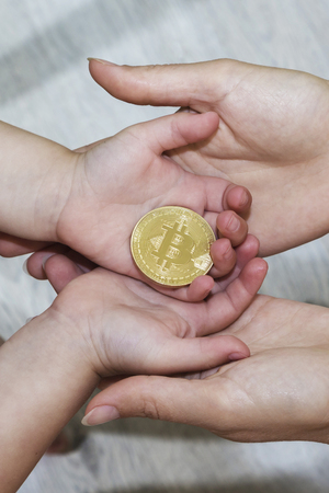 Bitcoin concept. Children share bitcoin. Child's hands and bitcoinの写真素材