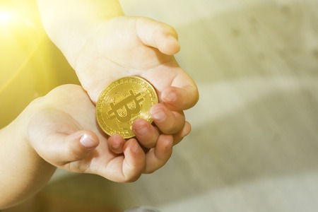 Bitcoin concept. Children share bitcoin. Child hand and bitcoinの写真素材