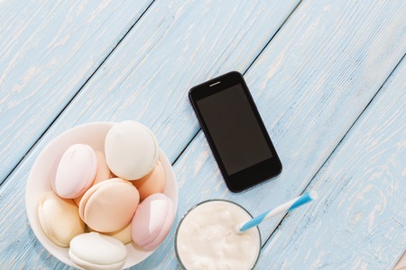 the marshmallow is next to the phone and a Cup coffee. Coffee-break.の写真素材