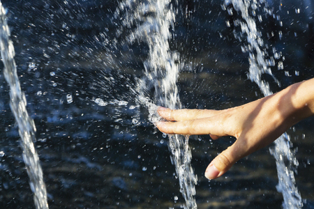 Hand of a girl in a spray of water from a fountain.の写真素材