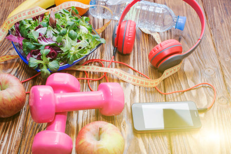 Fresh organic vegetables with dumbbells on a wooden countertop, diet, and the concept of healthy...