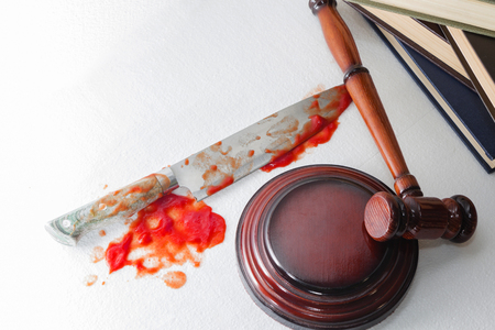 Conceptual image of a sharp knife with blood on the background of the judge's hammer. Justice.の写真素材
