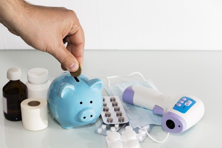A piggy bank sits on top of pills to pay for rising drug prices. Health care.の写真素材