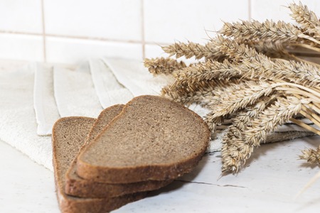 bread loaf and wheat ears on light background