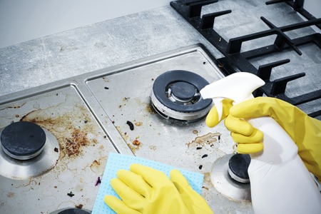 Cleaning a gas stove with kitchen utensils, household concepts, or hygiene and cleaning.の写真素材