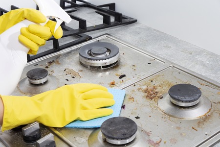 Cleaning a gas stove with kitchen utensils, household concepts, or hygiene and cleaningの写真素材