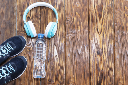 Sports equipment. Sneakers, water and headphones on wooden background.の写真素材
