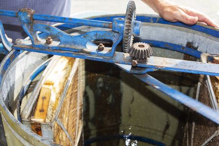 The production of honey from the honeycomb. natural honey dripping. An old honey extractor