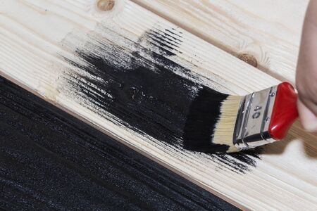 painting a wooden Board in black. a jar of black paint and a brushの写真素材