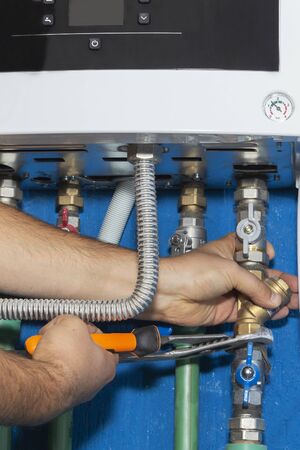 Plumber attaches to pipe gas boiler using adjustable wrenchの写真素材