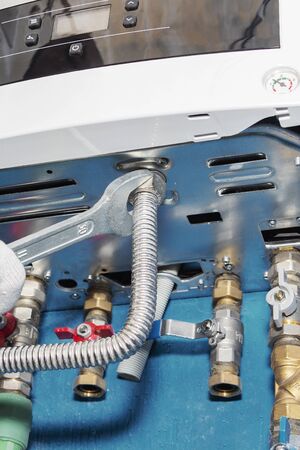 Plumber attaches to pipe gas boiler using adjustable wrenchの写真素材