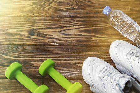 running shoes with dumbbells and a bottle of water on a wooden background. Healthy lifestyleの写真素材