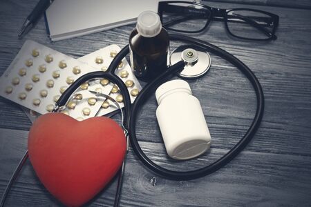 A heart with a stethoscope lies on a wooden background. Healthy heartの写真素材