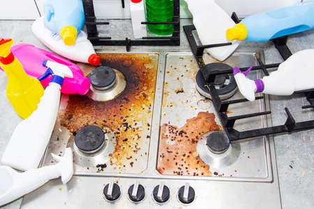 dirty kitchen stove, empty and full bottles of detergents around.
