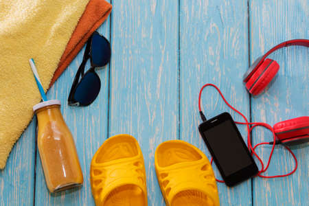 phone with headphones and sunglasses on a blue background, on a summer beach.