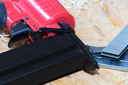 Red pneumatic construction stapler and a stack of staples for the stapler.の写真素材