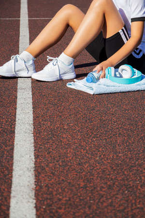 a female runner rests after a hard run on a sports field. Workout.
