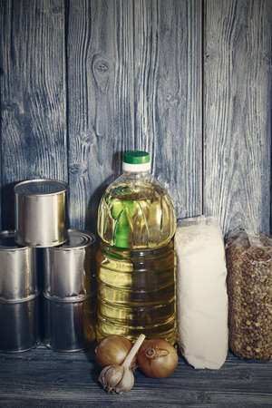 canned food and vegetable oil on a wooden shelf, food crisis.の写真素材