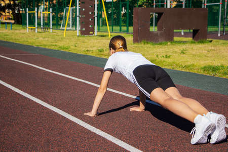 a teenage girl does push-UPS on the Playground. Fitness, sports, health.