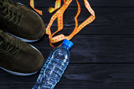 sneakers and a bottle of water on a black wooden background. The concept of a healthy lifestyle