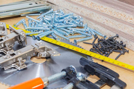 Screws, confirmations for furniture, tape measure, clamp, lie on the table. Furniture productionの写真素材