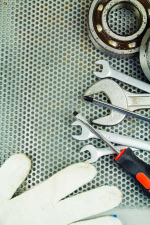 Metalworking tools, steel parts, a wrench, on the background of a metal latticeの写真素材