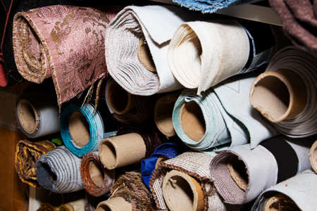 there are different rolls of fabric and leatherette on the shelfの写真素材