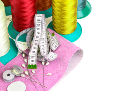 Sewing on a white background, reels with threads, needles and pieces of fabric.