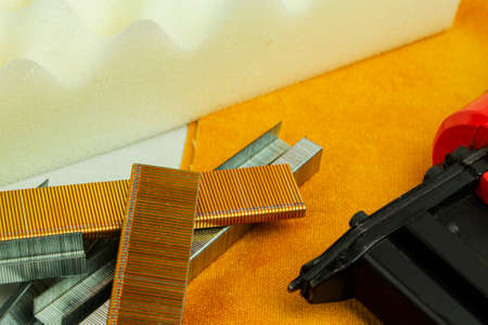 a piece of foam rubber and a stapler for clogging staples, upholstered furniture production.